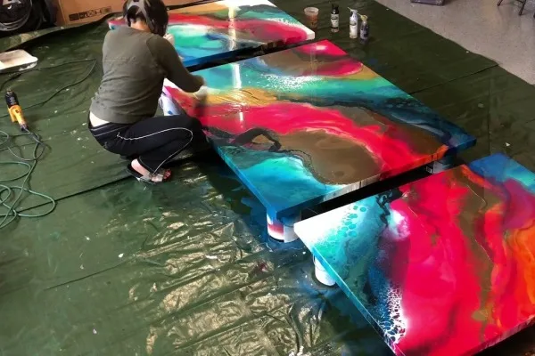 uma pessoa e tres mesas resinadas