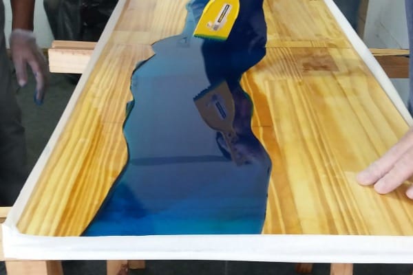 homens resinando mesa madeira